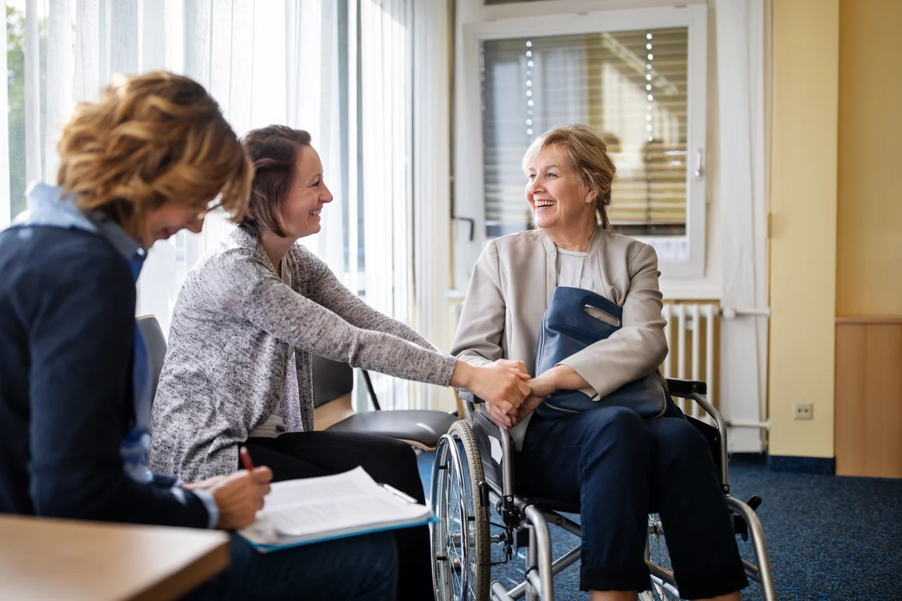 A woman in a wheelchair speaking to two other women